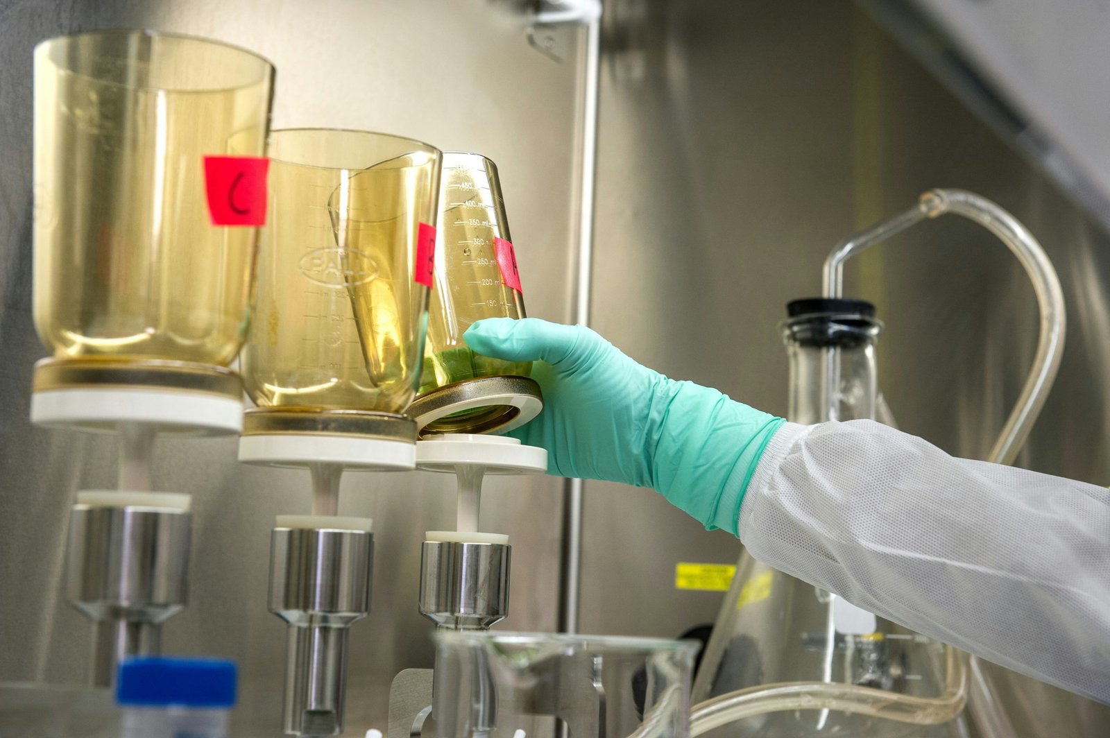 Gloved laboratory worker handling samples beside bioprocessing equipment
